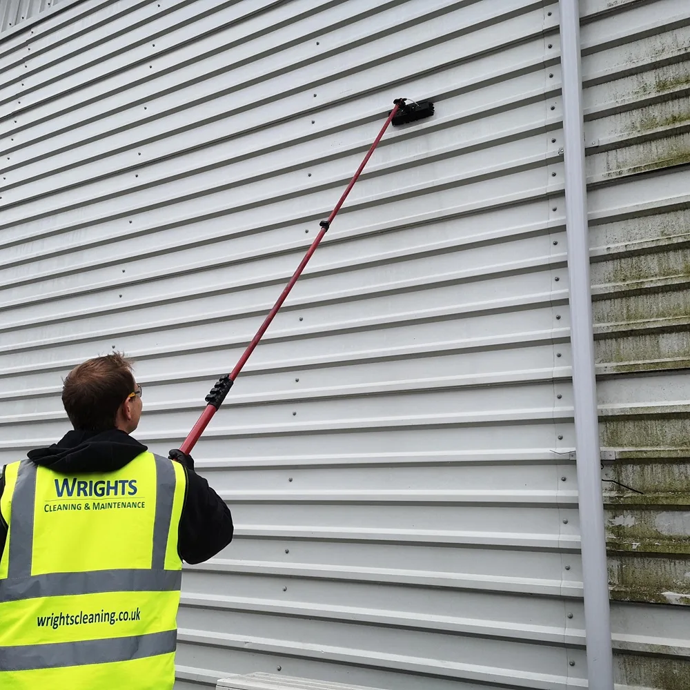 Cladding cleaned with a water-fed pole, next to panels still covered in algae