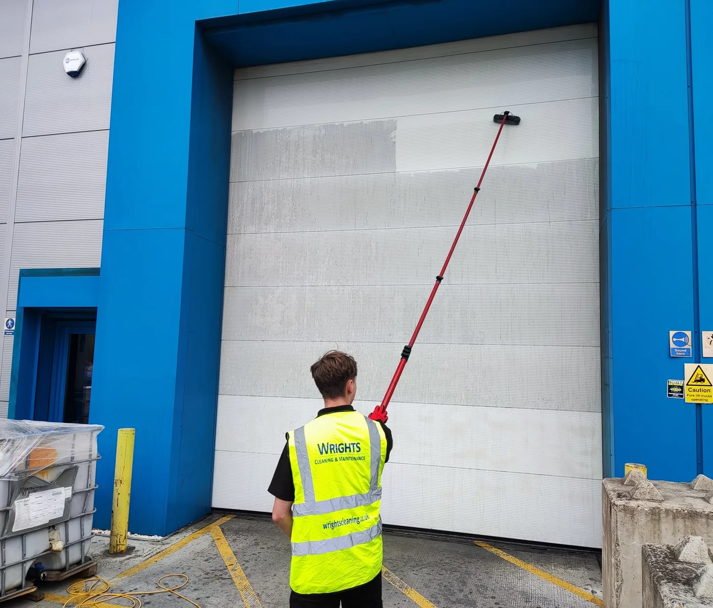 Wrights Cleaning operative cleaning an industrial unit with a water-fed pole