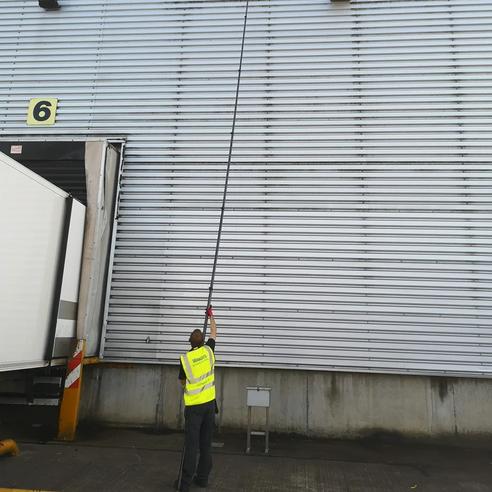 Water-fed pole reaching the top of a warehouse wall while the operative stays on the ground